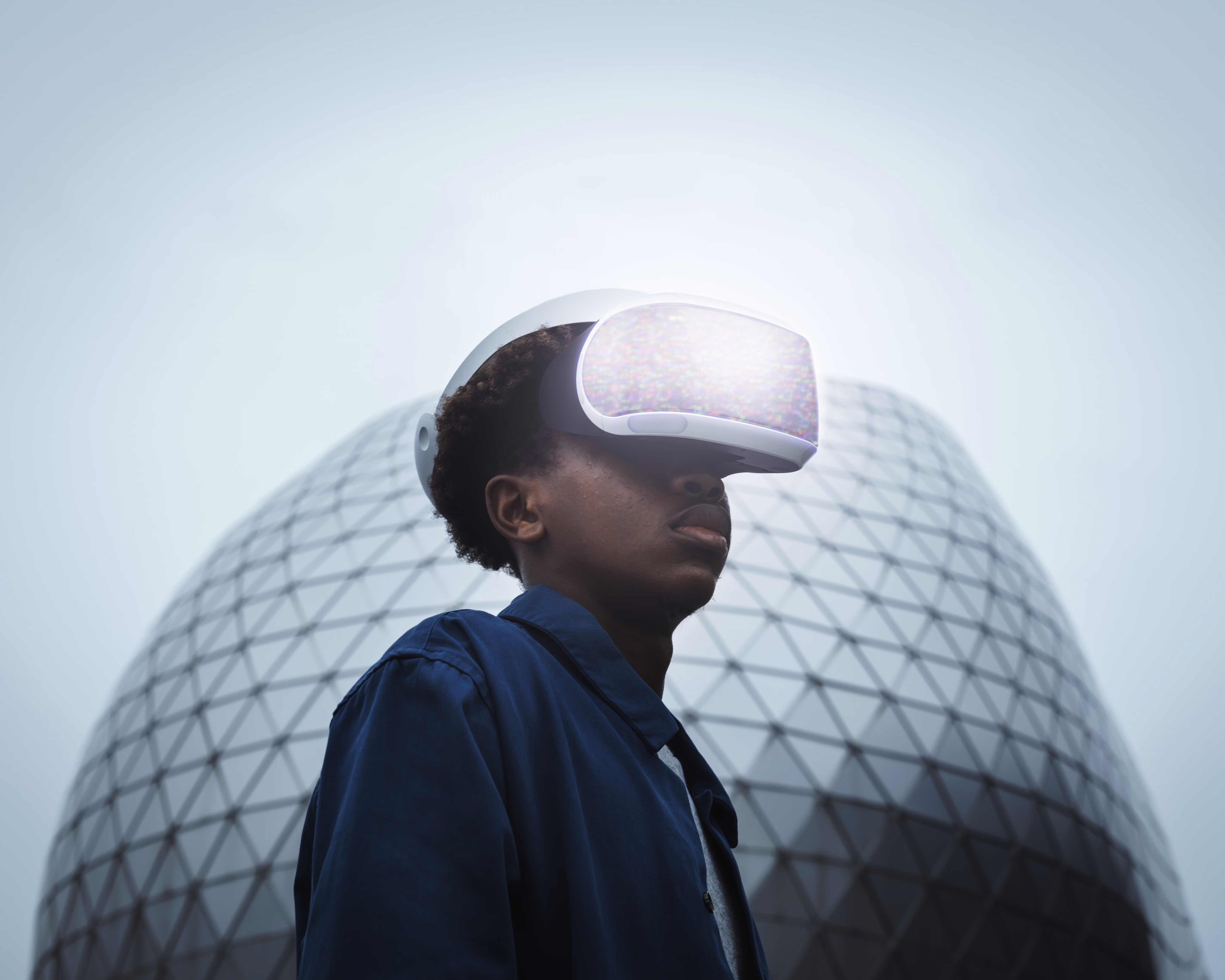 Imagem conceptual de um homem a usar óculos de realidade virtual no exterior, com um edifício moderno envidraçado ao fundo.